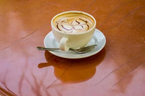 Simple cappuccino on a brown round table Stock Photos
