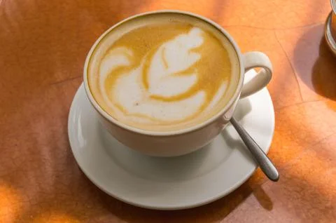 Simple cappuccino on a brown round table Stock Photos