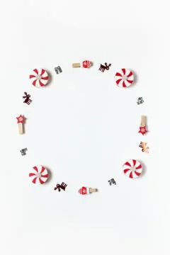 Simple Christmas composition. Round frame of clothespins, candy-bulbs, deer c Stock Photos