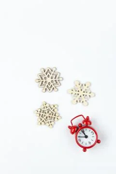Simple Christmas composition. Small analog red clock, wooden snowflakes on wh Stock Photos