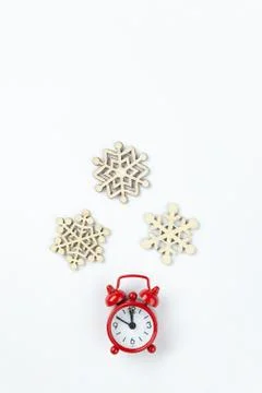 Simple Christmas composition. Small analog red clock, wooden snowflakes on wh Stock Photos