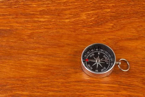 Simple compass on brown wood surface 库存照片