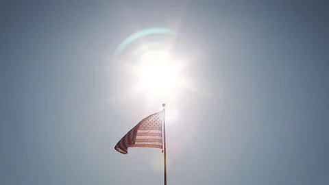 A simple composition of an American flag flying backlit with a sunburst. Stock Footage 115333330