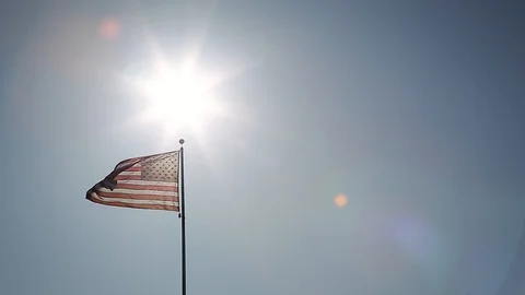 A simple composition of an American flag flying backlit with a sunburst. Stock Footage 115333510