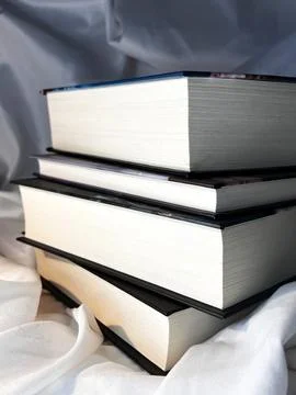 A simple composition of many books, stack or pile of books on white textile.. Stock Photos