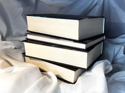 A simple composition of many books, stack or pile of books on white textile.. Stock Photos