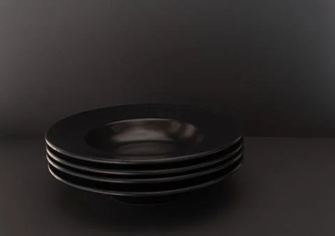 A simple composition of a stack of black plates on a black background. 스톡 사진