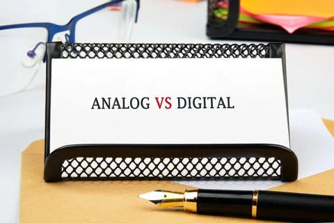 A simple desk scene features a card stating analog versus digital, symbolizin Stock Photos