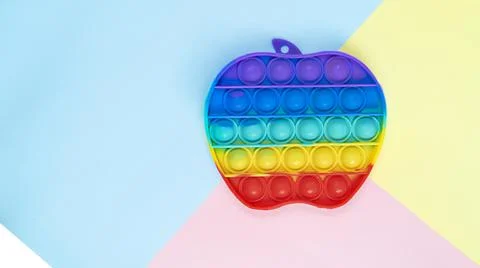Simple Dimple touch multi-colored toy in the form of an apple on a colored Stock Photos