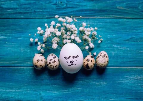Simple DIY easter egg with drawn cute face surrounded with quial eggs Stock Photos