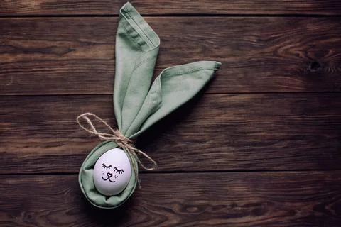 Simple DIY easter egg with drawn cute face. Easter bunny napkin ears Foto stock