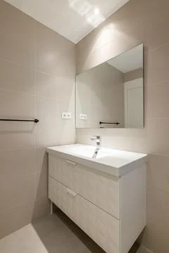 Simple, empty and modern bathroom with beige tiles, sink and mirror Photos