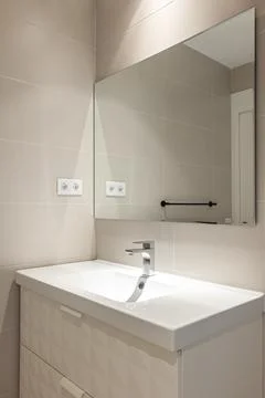 Simple, empty and modern bathroom with beige tiles, sink and mirror Stock Photos