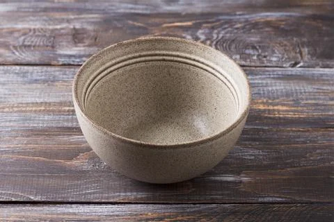Simple empty beige craft ceramic bowl on wooden table, rustic style, mockup, for Stock Photos