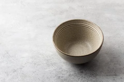 Simple empty beige craft ceramic bowl on a gray textured background, mockup, for Stock Photos