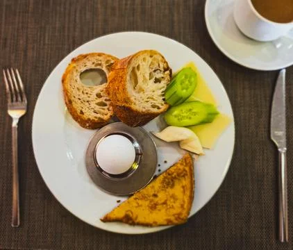 Simple European breakfast with egg, bread, cheese and vegetables on white plate Stock Photos