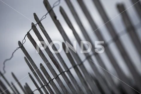 Simple fence with wire and narrow wooden boards that are broken in un-even lengt Stock Photos