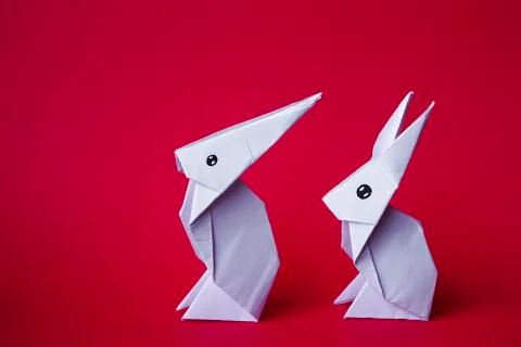 Simple flat lay out. two White rabbits paper origami on clear background with Stock Photos