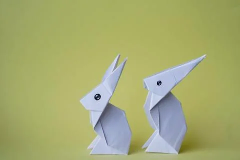 Simple flat lay out. two White rabbits paper origami on clear background with Stock Photos