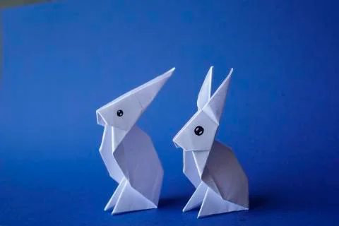 Simple flat lay out. two White rabbits paper origami on clear background with Stock Photos