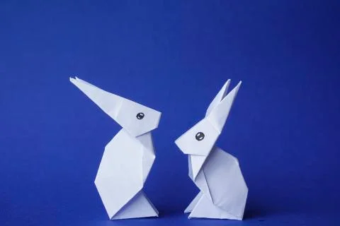 Simple flat lay out. two White rabbits paper origami on clear background with Stock Photos