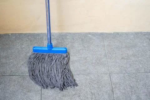 A simple floor mop propped against the wall Stock Photos