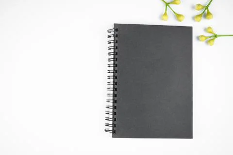 Simple gray colored paper diary and some small flowers before a white backgro Stock Photos