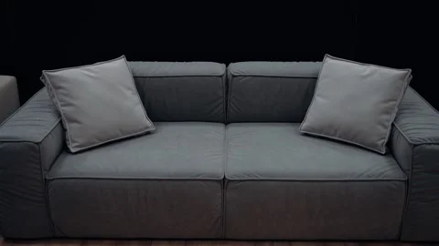 A simple gray sofa with cushions of the same color, shot slowly on a black Stock Footage 231508102