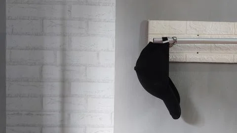 A simple hat hanging on a clothes hanger in a bedroom Stock Photos