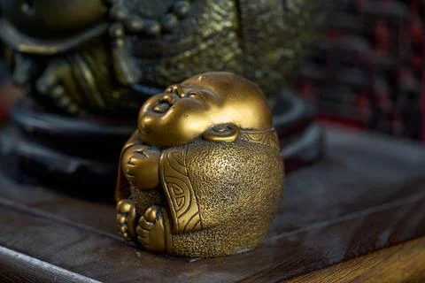 A simple-looking bronze statue of Maitreya Buddha on the tea table in an ol.. Stock Photos