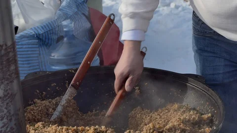 Simple meal. The cook puts buckwheat porridge on plates from a large cauldron. Vídeos de archivo 124997997