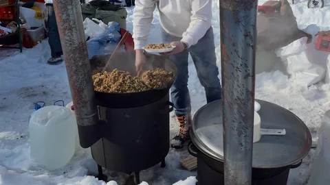 Simple meal. The cook puts buckwheat porridge on plates from a large cauldron. Video stock 124998000