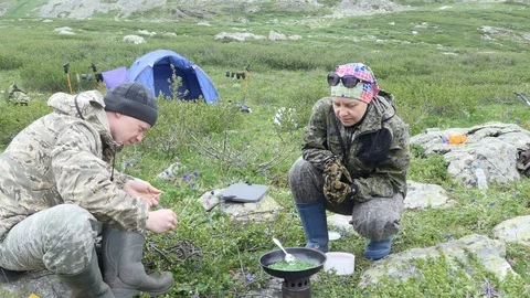 Simple meal. A man throws chips into the camp stove. Video stock 118974938