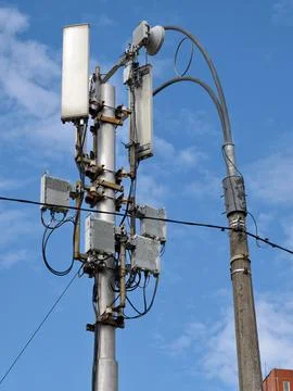 A simple mobile network tower placed on a low pole near a roadside lamp Stock Photos