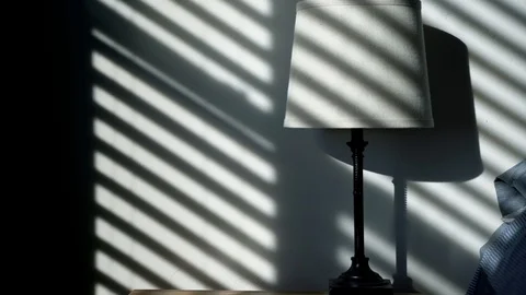 Simple modern nightstand lamp with shadows from window blinds casting a Stock Footage 100227793