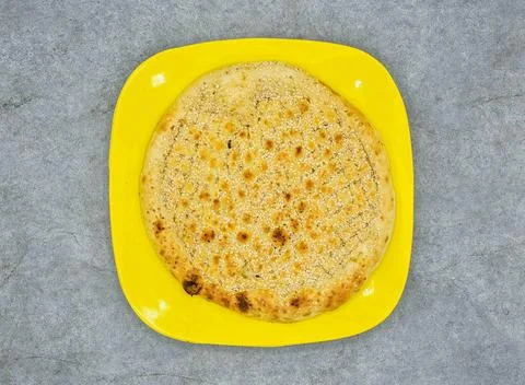 Simple Naan in yellow plate top view on grey background Foto stock