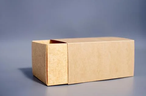 Simple open brown cardboard box on gray surface Stock Photos