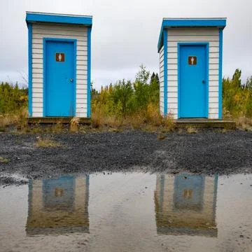 Simple outhouses mirrored in puddle Stock Photos
