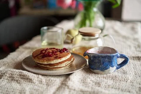 Simple pancake breakfast with jam and apple, tea served on a kitchen table Stock Photos