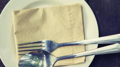 Simple place setting with fork spoon and napkin on white plate Stock Photos
