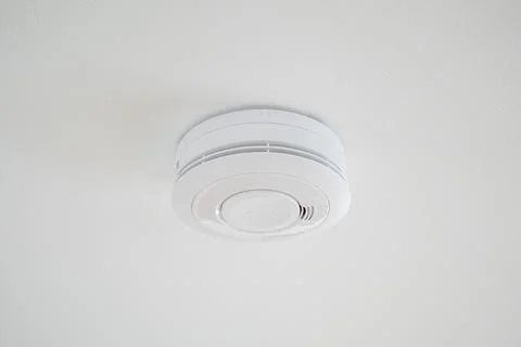 Simple plain fire alarm detector on the white ceiling Stock Photos