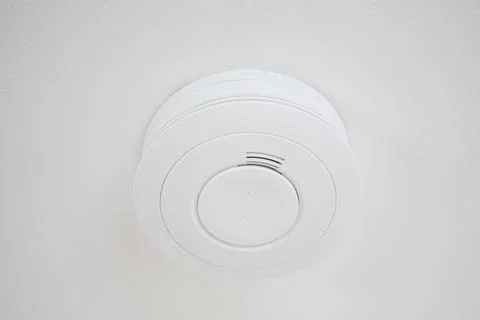 Simple plain fire alarm detector on the white ceiling Stock Photos