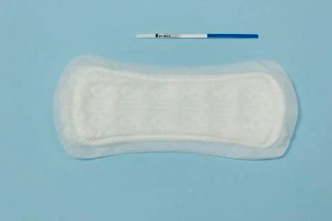 Simple pregnancy test and an empty pad.the concept of no menstruation during Stock Photos