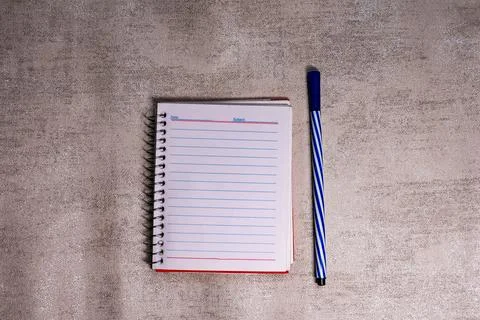 Simple red spiral-bound notebook with lined paper beside a single Stock Photos