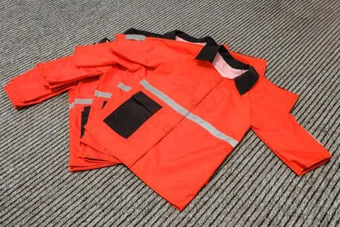 Simple red work clothes stacked in a pile. Sewing of standard overalls. Stock Photos