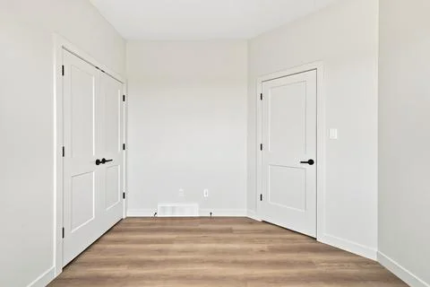 Simple room features white walls and light wood flooring 库存插图