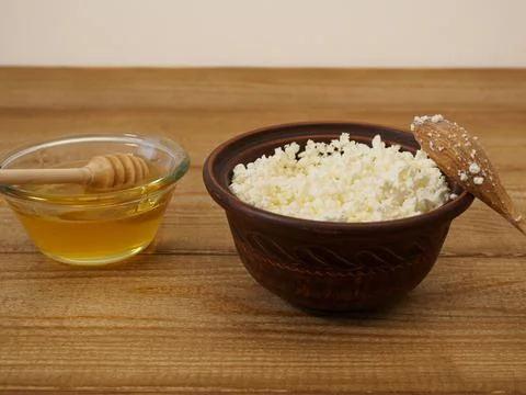 Simple rustic breakfast with cottage cheese in a clay bowl and honey on a wooden Stock Photos
