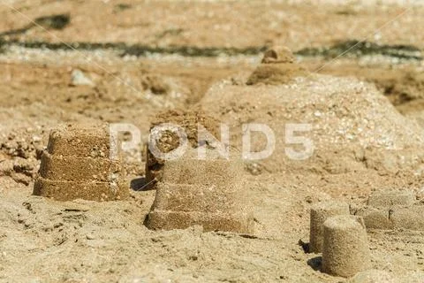 Photograph: Simple sand towers and castle on a sunny sandy sea beach ...