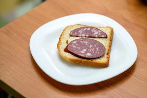 Simple sandwich made of bread and a half slice of smoked sausage is placed on Stock Photos