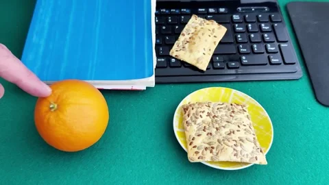 Simple Snack Setup: Crackers and Orange on Office Desk 스톡 동영상 327775254